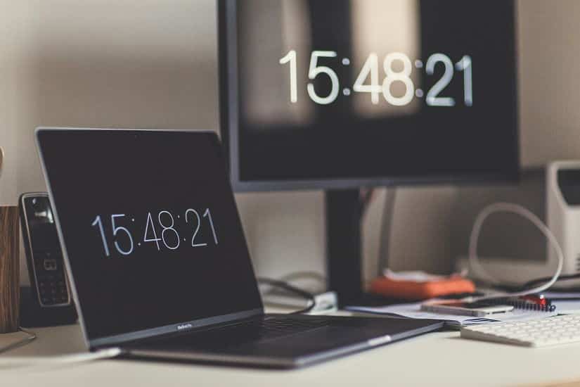 Notebook and monitor with a clock on it